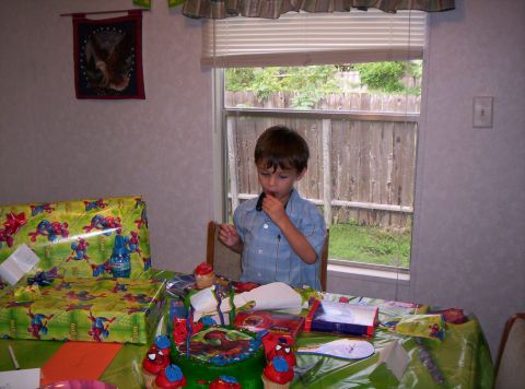1986 Ford Bronco - A young boy enjoys a treat at his birthday party, surrounded by gifts and a themed cake.