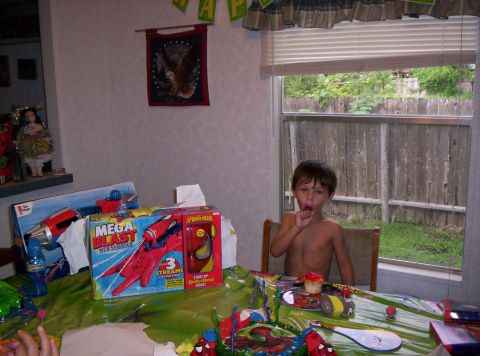 1986 Ford Bronco - A young boy sits at a table laden with birthday presents and a cake.
