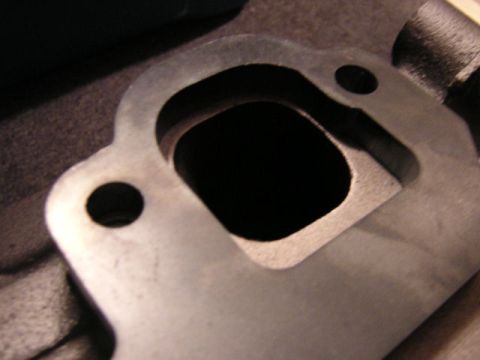 1979 Ford Bronco - Close-up of a metal exhaust manifold flange, showing its mounting holes and exhaust port.
