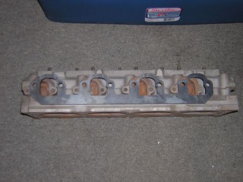 1979 Ford Bronco - A single engine cylinder head is shown, with exhaust ports visible and a gasket in place.
