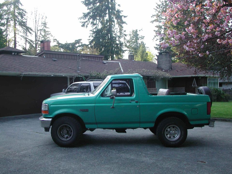 Teal 1990s Ford Bronco with hardtop removed, side view in a driveway