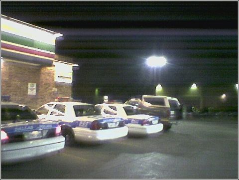 1993 Ford Bronco - Police vehicles are parked in front of a store, illuminated by streetlights.