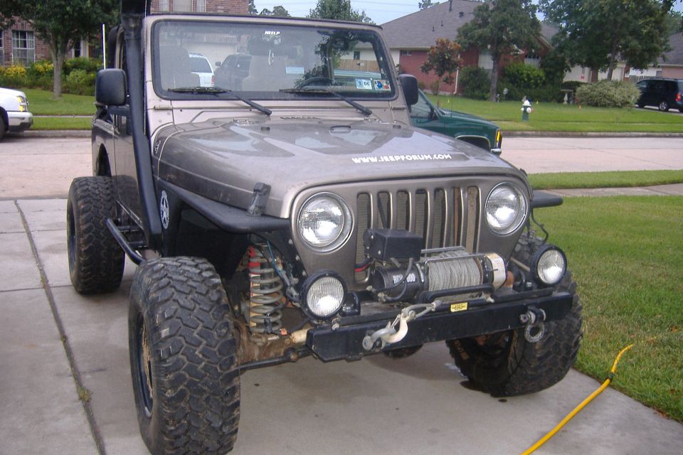 Front view of a tan 2004 Jeep Wrangler with a winch and snorkel