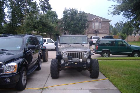 2004 Jeep Wrangler - A gray 2004 Jeep Wrangler is parked in a driveway with other vehicles, a winch mounted on the front bumper.