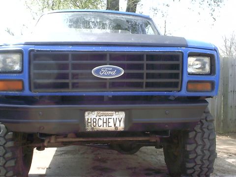 1983 Ford Bronco - This blue Ford pickup truck features a prominent grille with the Ford logo and a custom license plate.