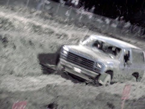 1983 Ford Bronco - A 1983 Ford Bronco navigates a muddy terrain, showing its front 3/4 profile as it gets stuck.