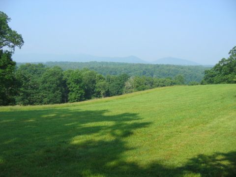 1985 Ford Crown Victoria LTD - A wide shot of a rolling green landscape with trees and distant mountains.