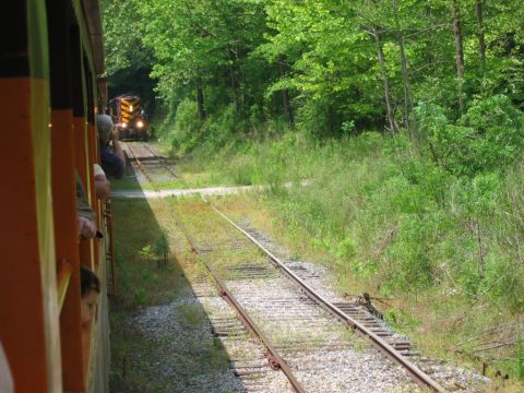 1985 Ford Crown Victoria LTD - Two trains on parallel tracks, one in the distance approaching a tunnel, viewed from the side of a passenger train.
