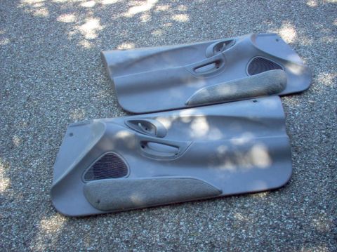 1994 Ford Probe - Two gray interior door panels are shown laid out on a gravel surface, likely for sale or parts.