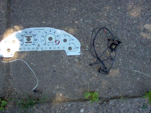 1994 Ford Probe - A car's instrument cluster and associated wiring are laid out on a concrete surface.