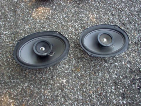 1994 Ford Probe - Two oval car speakers are shown lying on a gravel surface.