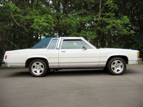 1985 Ford LTD Crown Victoria - Side profile of a white 1985 Ford Crown Victoria LTD coupe a blue vinyl roof and chrome trim.