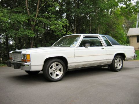 1985 Ford LTD Crown Victoria - Side view of a white 1985 Ford Crown Victoria LTD with aftermarket wheels.