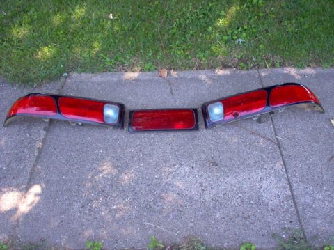1994 Ford Probe - Set of three taillight assemblies and a center reflector, likely from a 1994 Ford Probe, laid out on a sidewalk.