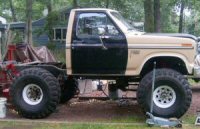 1985 Ford LTD Crown Victoria - A customized pickup truck sits outdoors with large off-road tires and a two-tone paint scheme.