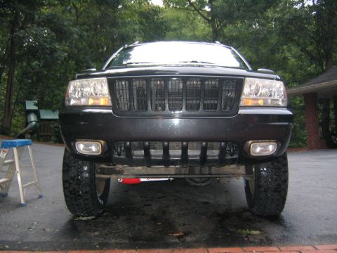 2005 Ford F-250 - Front view of a black Jeep Grand Cherokee, possibly a 2004 model, with modified grille and fog lights.