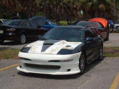 1989 Ford Probe - A sports coupe with custom bodywork sits in a parking lot, with other vehicles visible in the background.