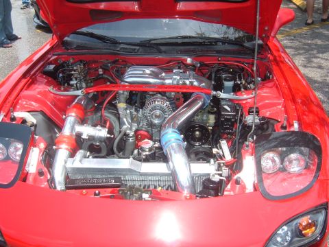 1989 Ford Probe - The engine bay of a red car is shown, a prominent rotary engine with twin turbochargers and a custom intake system.