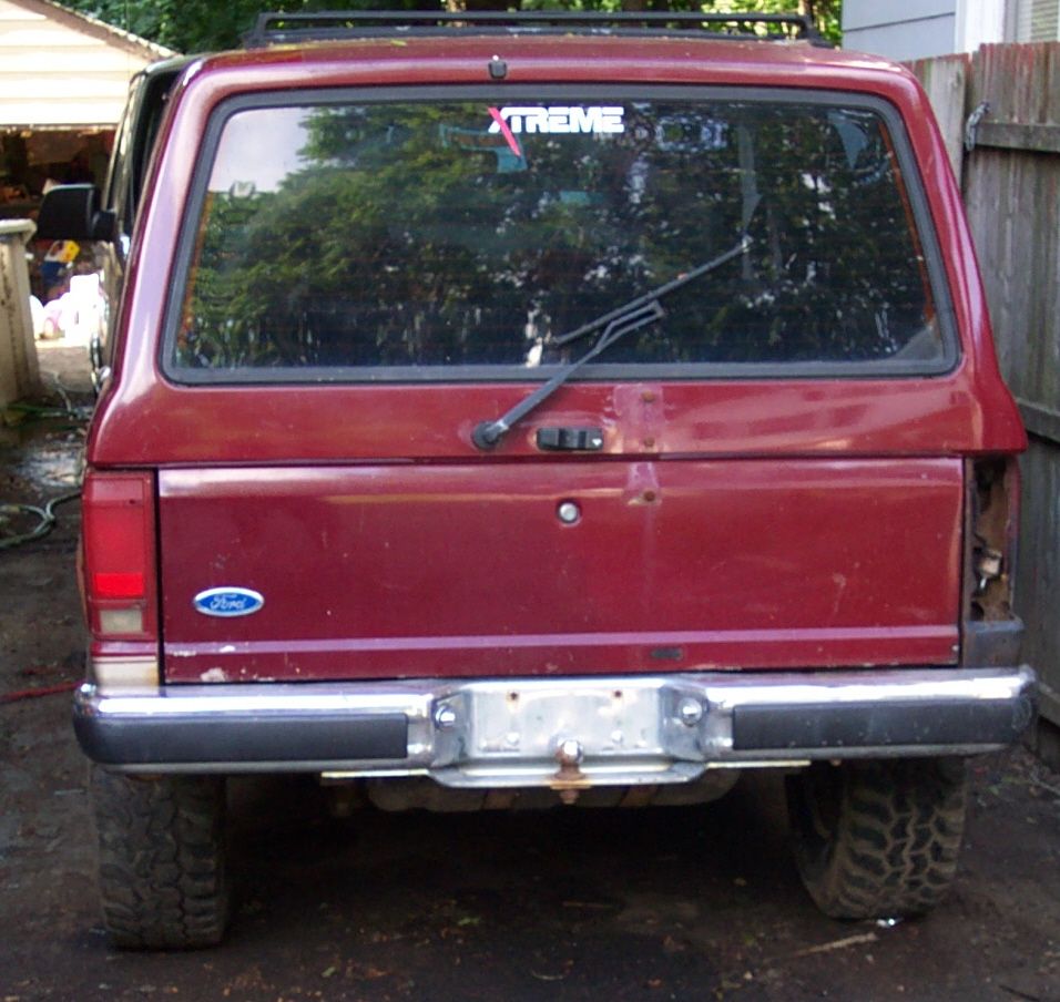 Rear view of a red Ford Bronco II with a roof rack and an XTREME sticker on the rear window