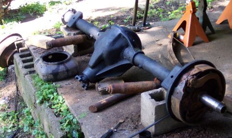1978 Ford Bronco - A rear axle assembly, likely for a Ford Bronco, is shown disassembled and resting on concrete blocks outdoors.