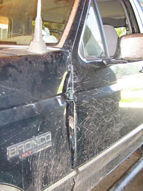 1995 Ford Bronco - Close-up of a 1995 Ford Bronco XLT's side, detailing mud and a slight imperfection on the door.