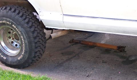 1979 Ford F-250 - A detached driveshaft rests on the ground near the wheel of a white truck.