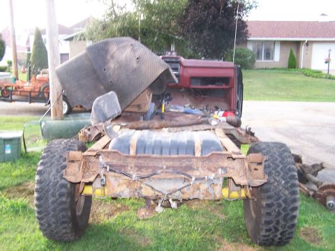 1986 Ford Bronco - The vehicle's frame, fuel tank, and large tires are heavily rusted, indicating it is in disrepair.