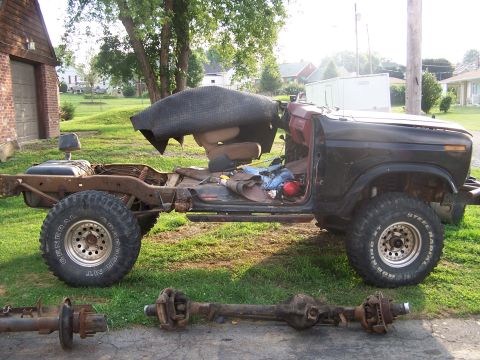 1986 Ford Bronco - This disassembled SUV chassis, likely from the early 1980s, has had its axles removed and placed on the ground.