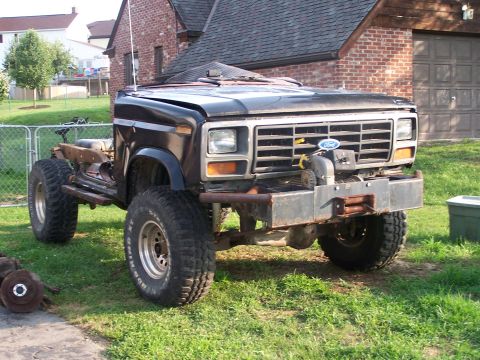 1986 Ford Bronco - This modified 1986 Ford Bronco features a custom front bumper, winch, and oversized tires, with its rear section removed.