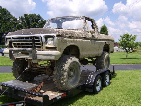 1978 Ford Bronco - A heavily modified 1978 Ford Bronco, caked in mud, is loaded onto a trailer.