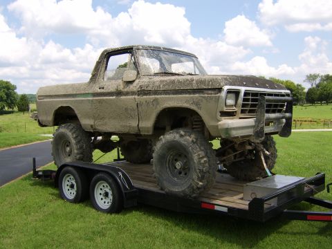 1978 Ford Bronco - This heavily modified 1978 Ford Bronco, caked in mud, is being transported on a trailer.