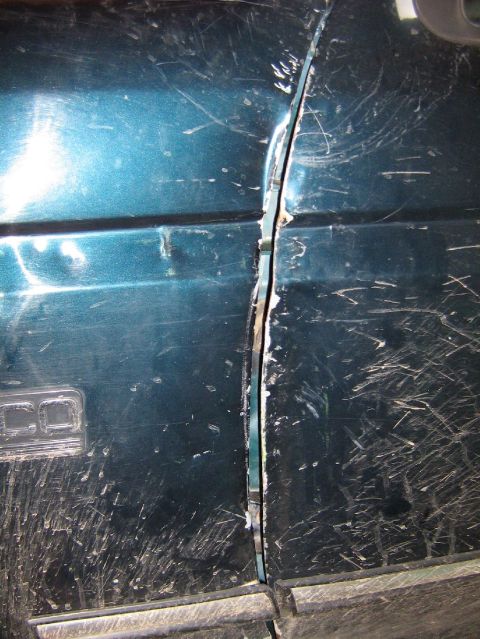 1995 Ford Bronco - The door gap on this teal vehicle is significantly misaligned, indicating potential body damage.