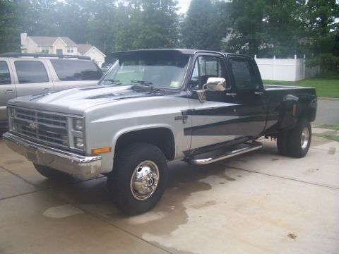 2005 Dodge 1500 - A two-tone dually pickup truck is parked in a driveway, with an SUV visible in the background.