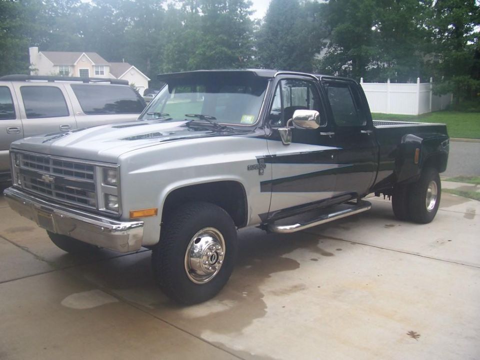 Two-tone dually pickup truck parked in a driveway. Another SUV is parked behind it