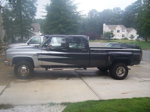 2005 Dodge 1500 - A black and silver crew cab pickup truck is parked on a driveway, with another vehicle visible behind it.