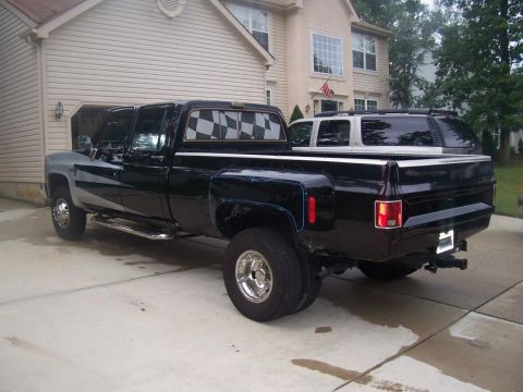 2005 Dodge 1500 - This older model dually pickup truck has a two-tone paint job and checkered window tint. An SUV is parked behind it.