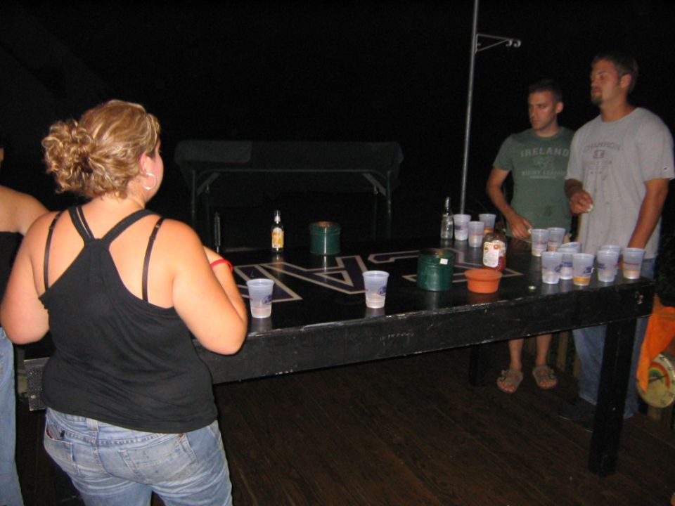 People gathered around a beer pong table with cups and bottles
