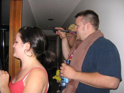 1986 Ford Mustang - A group of people are seen at a party, with one individual holding a bottle and another wearing a hat.