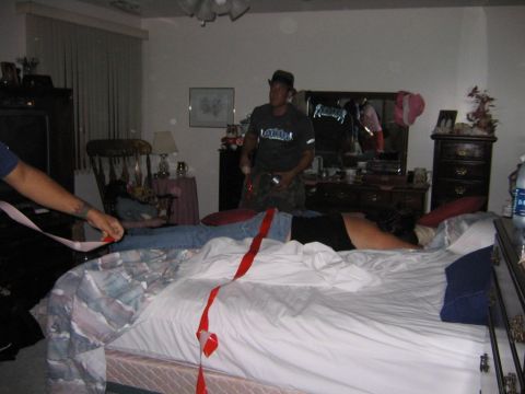 1986 Ford Mustang - A bedroom scene with people and red tape on the bed.