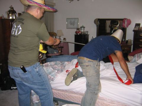 1986 Ford Mustang - Two men are engaged in an unusual activity in a bedroom, one wearing a sombrero and the other a bucket on his head.