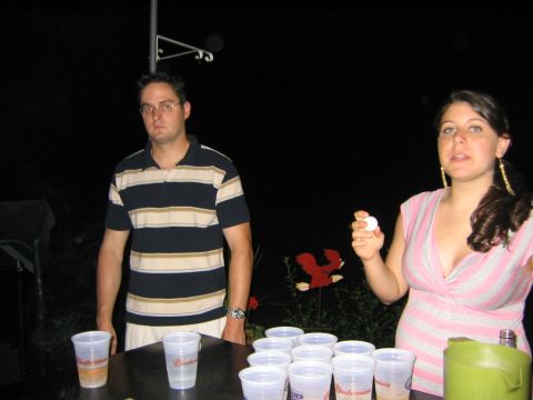 1986 Ford Mustang - Two people stand near a table set up for a game of beer pong at night.