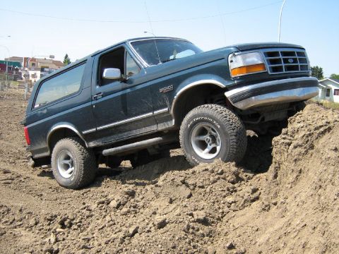 1995 Ford Bronco - Ford Bronco navigates a steep dirt incline, its off-road capability.