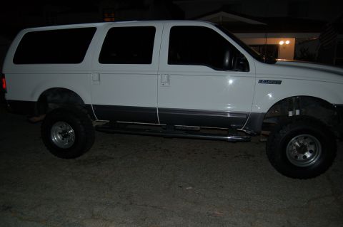 2001 Ford Excursion - Side profile of a white 2001 Ford Excursion, tinted windows and a lifted suspension.