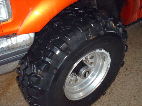 1991 Ford F-350 - Orange vehicle wheel and tire with off-road tread pattern.