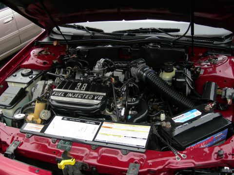 1992 Ford Taurus - The engine compartment of a red vehicle is open, revealing the V6 engine and various components.