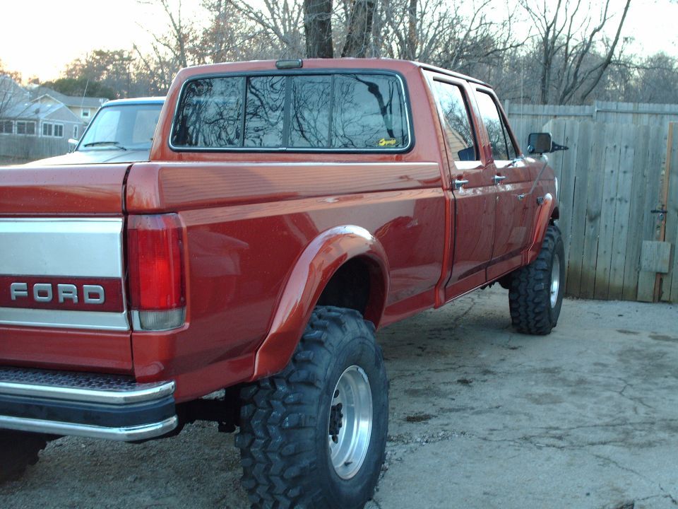 Red 1991 Ford F-350 pickup truck with large tires, seen from the rear quarter