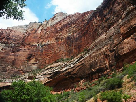 2001 Mercury Grand Marquis - A scenic view of a large, layered rock formation under a bright blue sky, with green foliage in the foreground. The Supermotors logo is vis…