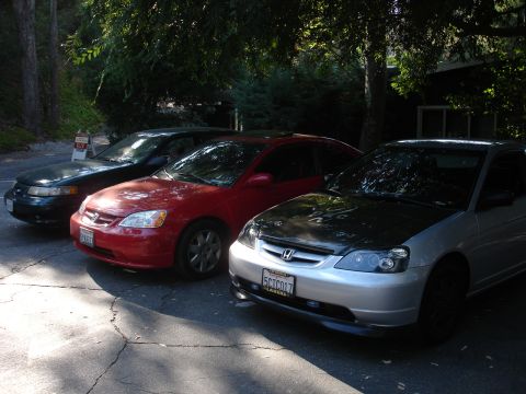 1995 Ford Taurus - Three cars are parked in a lot, including a silver Honda Civic and a red Honda Civic.