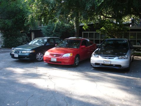 1995 Ford Taurus - Three cars are parked side-by-side in an outdoor lot.