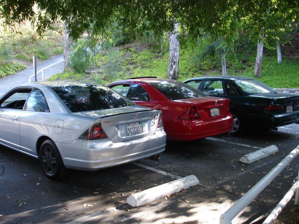 Silver coupe, red sedan, and dark sedan parked side-by-side